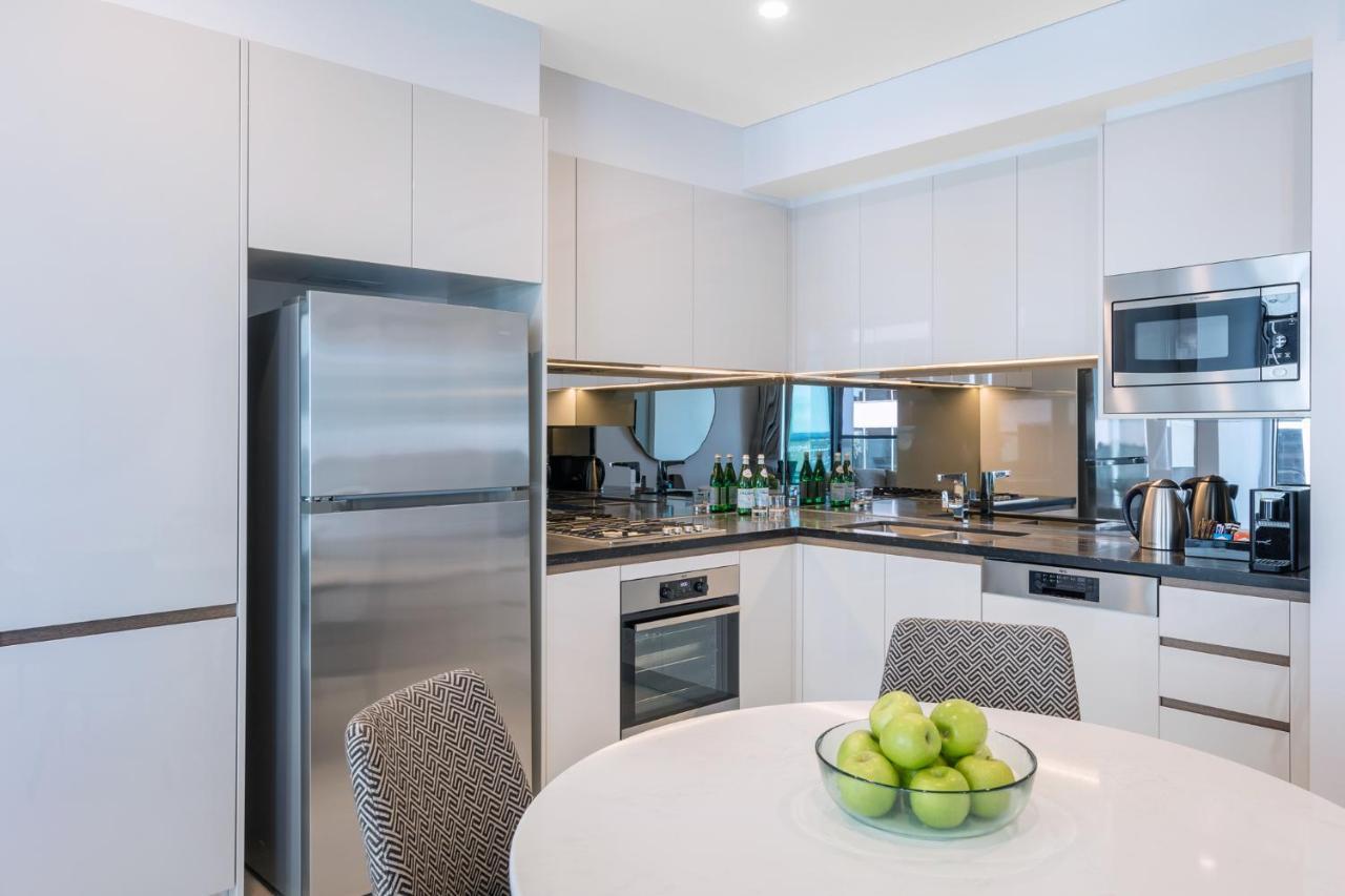 Meriton Suites Sussex Street, Sydney Exterior photo The photo displays a modern kitchen with a sleek design. It features light-colored cabinetry and a countertop with a polished finish. On the left, there is a stainless steel refrigerator. The kitchen is equipped with various appliances, including an 