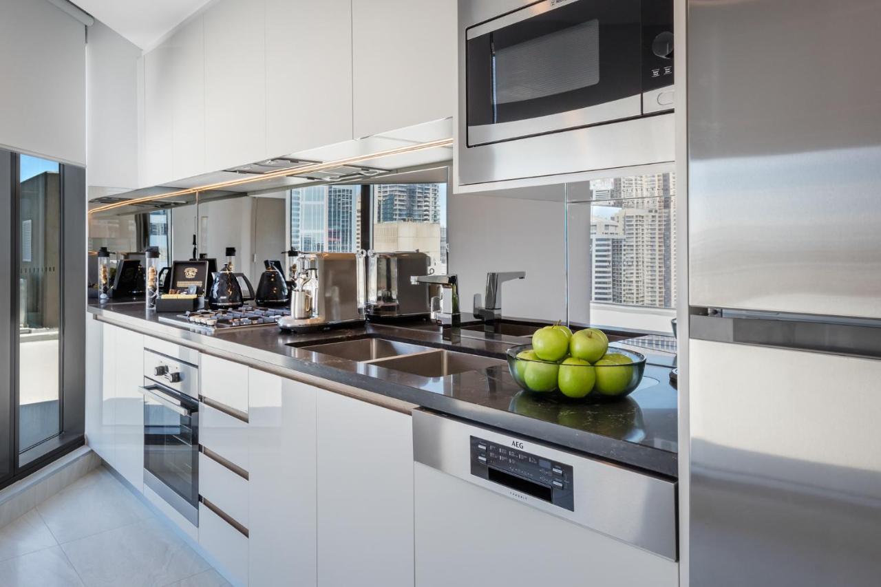 Meriton Suites Sussex Street, Sydney Exterior photo The photo shows a modern kitchen featuring sleek cabinetry and stainless steel appliances. There is a glossy countertop with a bowl of green apples as a decoration. The kitchen includes a built-in oven, a microwave, and other kitchen gadgets, along w