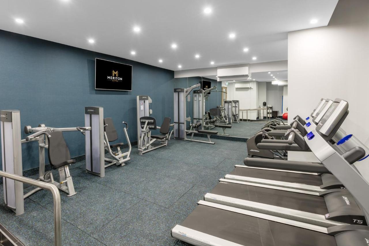 Meriton Suites Sussex Street, Sydney Exterior photo The photo shows a modern gym interior. The space features several pieces of exercise equipment, including weight machines and stationary bikes. The walls are painted a calming color, and the flooring is carpeted. There are also mirrors on the walls, 