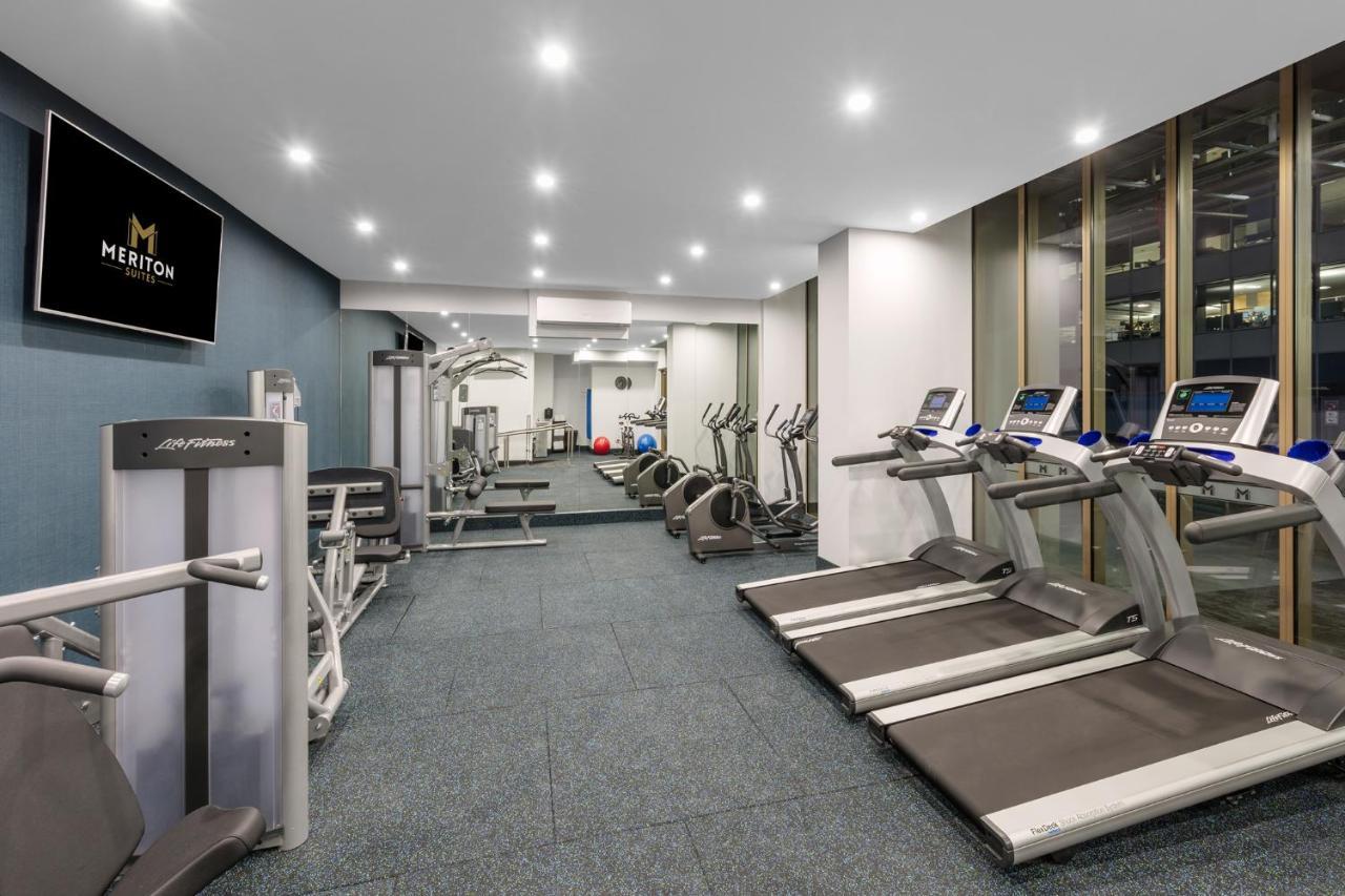 Meriton Suites Sussex Street, Sydney Exterior photo The photo shows a modern gym space. It features various exercise equipment, including several treadmills and elliptical machines positioned along one side. On the other side, there are weight machines and additional fitness equipment. The gym has a c