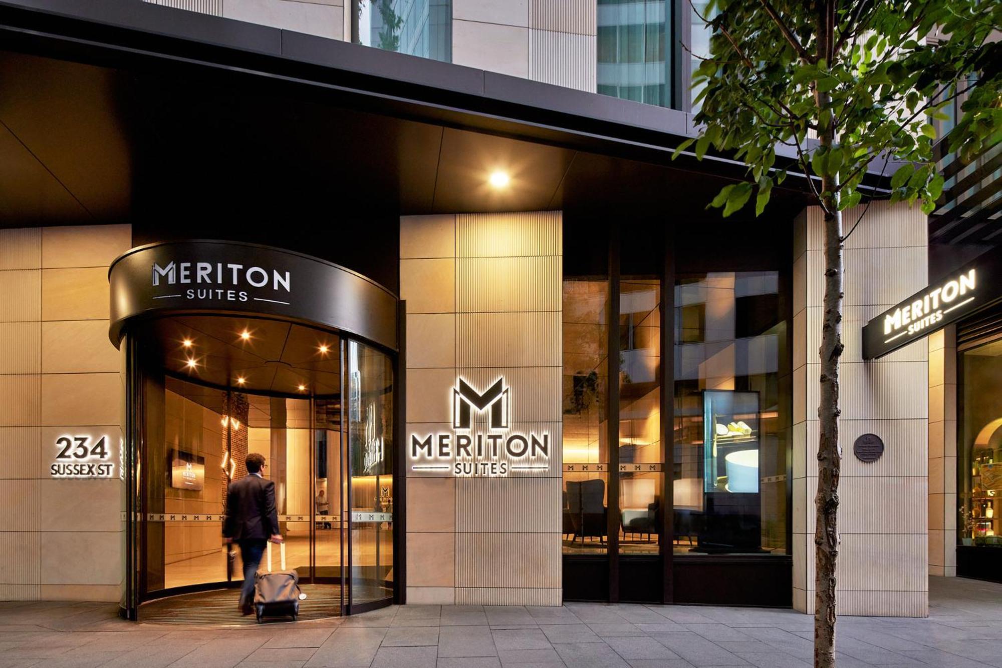 Meriton Suites Sussex Street, Sydney Exterior photo The photo shows the entrance of a hotel or suite establishment named "Meriton Suites." The entrance features a revolving door and a large, illuminated sign with the name "MERITON SUITES." The facade is modern and sleek, with a combination of glass an